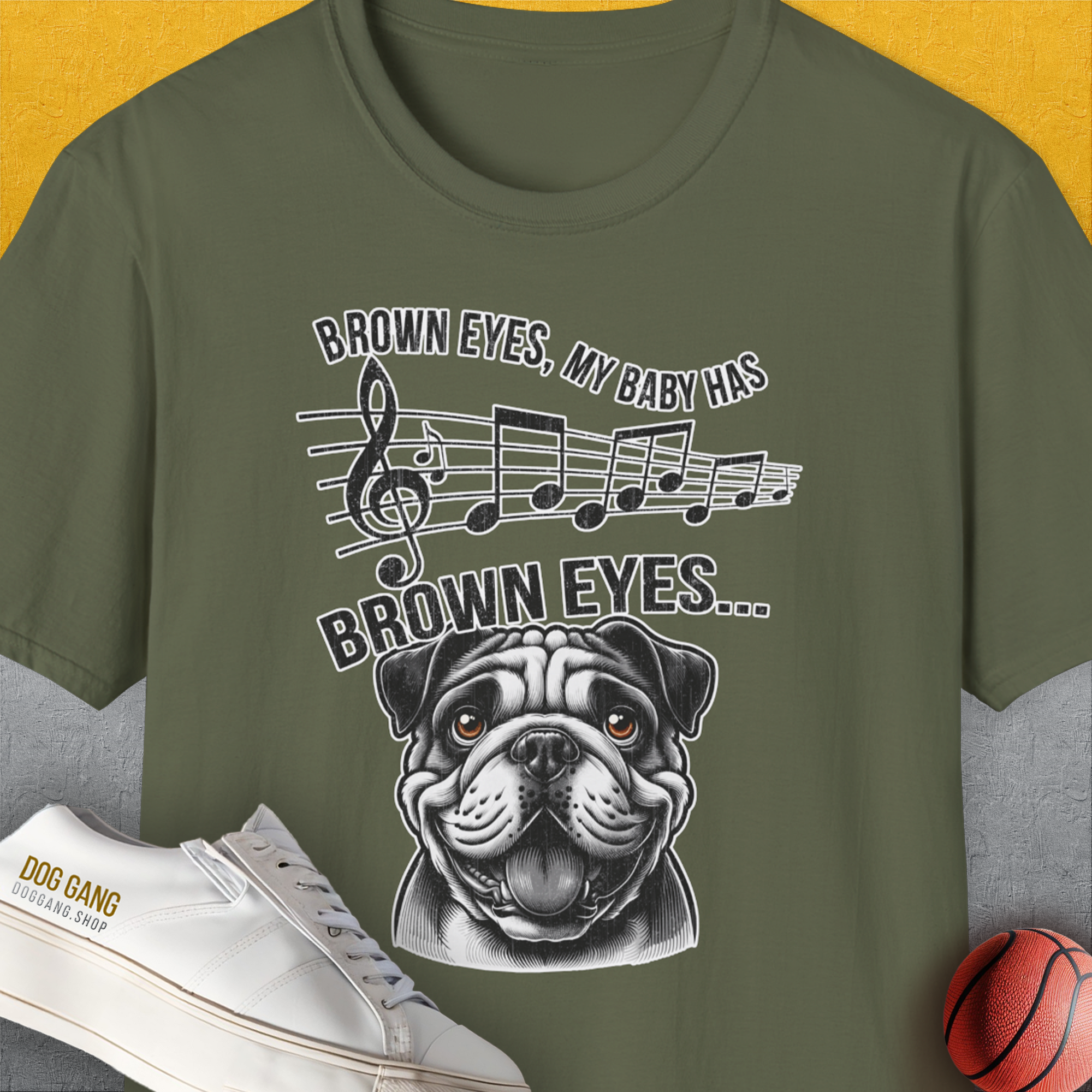 Military Green unisex t-shirt featuring a bulldog with musical notes, text: Brown Eyes, My Baby Has Brown Eyes… Perfect for any dog lover gift. Designed by Dog Gang.
