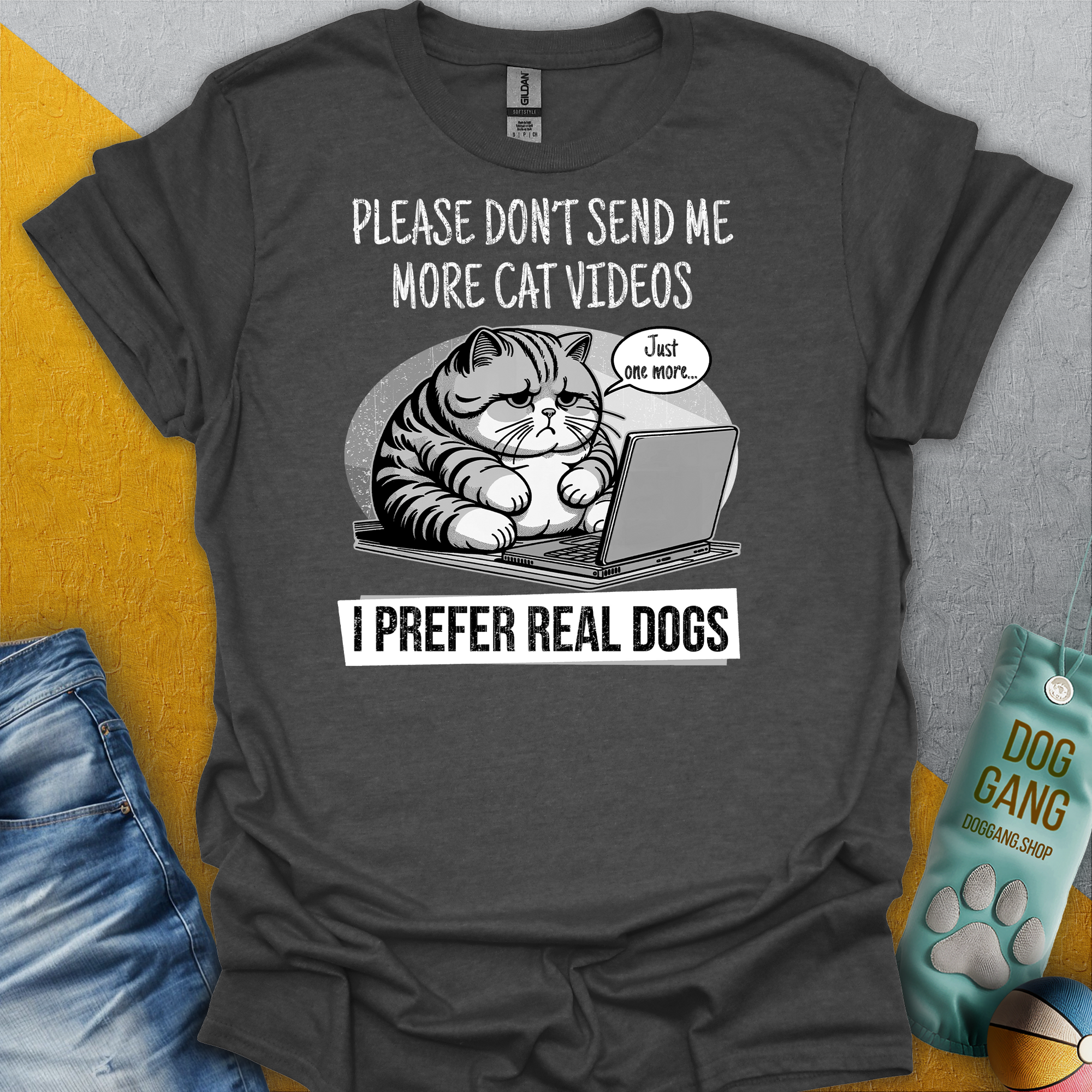 Das graue Unisex-T-Shirt der Cat Videos Series, zeigt eine Cartoon-Katze auf einem Laptop mit dem englischsprachigen Text: „Bitte schick mir keine weiteren Katzenvideos. Ich bevorzuge echte Hunde.“ Hergestellt aus 100 % Baumwolle. Design von Dog Gang.