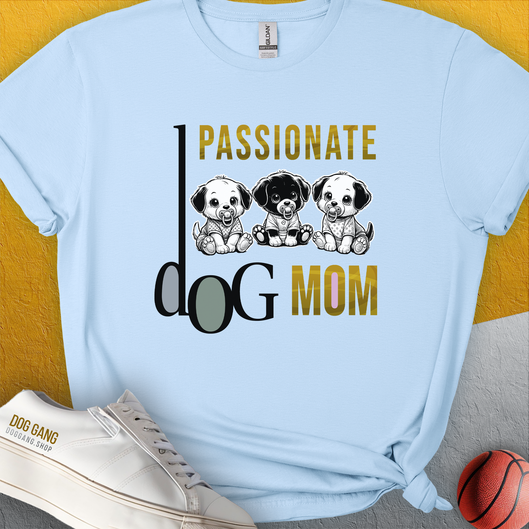The Dog Mom Series, Volume 6 unisex T-shirt is light blue and made from 100% cotton. It features Passionate Dog Mom text with three illustrated puppies. Perfect for any dog lover. Designed by Dog Gang.