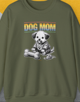 The sweatshirt features a cartoon puppy with a fabric bone and fabric mouse, with Dog Mom text in a sunset gradient. Perfect for any dog person. Designed by Dog Gang.