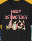 The black unisex t-shirt from the Easily Distracted By Dogs Series, Volume 2 highlights a dog-themed design with pink text and playful dog illustrations creatively forming the word dogs. The illustrations include breeds like Dalmatian, Golden Retriever, Pug, Poodle, Dachshund, Bulldog, Chihuahua, Husky and more. Designed by Dog Gang.