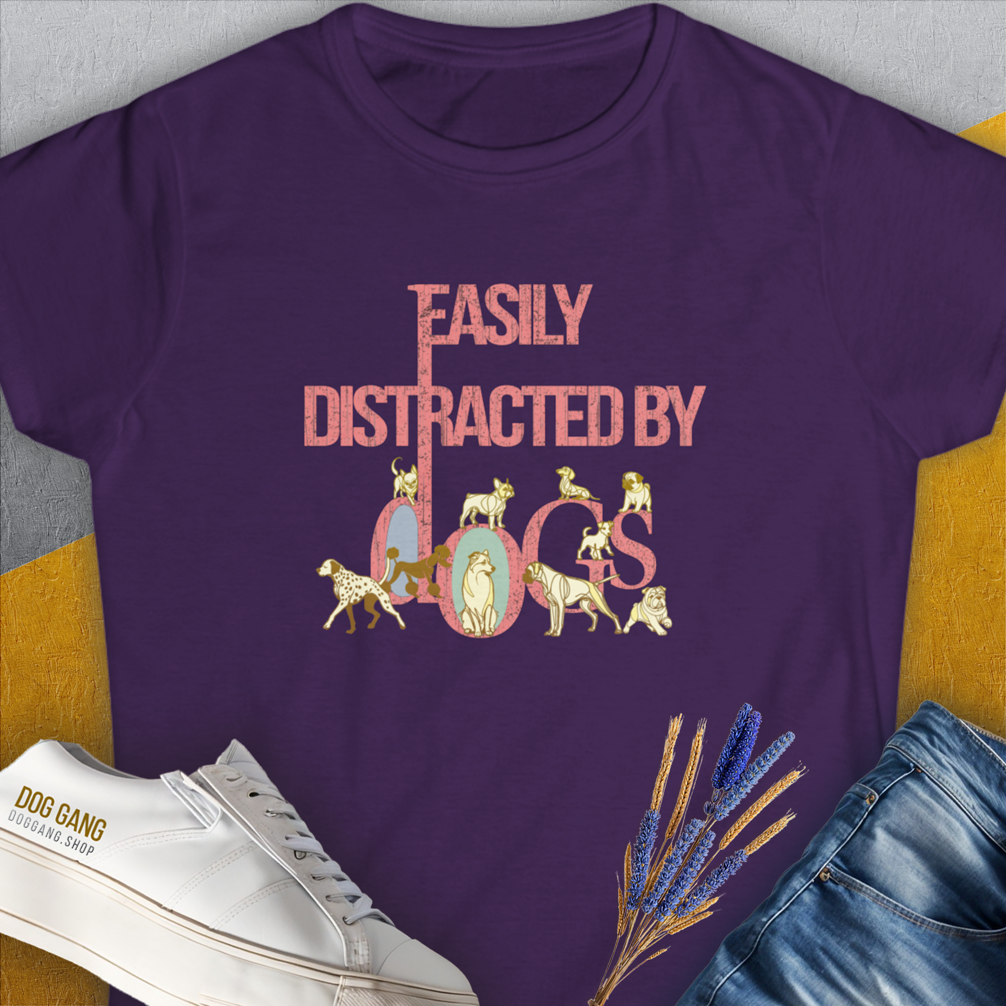 The Easily Distracted By Dogs Series, Volume 2 Womens T-Shirt in purple features the phrase in pink with a Dalmatian, a Golden Retriever, a Pug, a Poodle, Dachshund, French Bulldog, Chihuahua, Husky and more around the letters. Designed by Dog Gang.