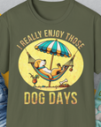 Das lustige Unisex-T-Shirt „I Really Enjoy Those Dog Days“ ist militärgrün und zeigt einen Hund in einer Hängematte mit einem Getränk. Aus weicher Baumwolle für mehr Komfort. Design von Dog Gang.