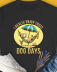 This puppy print tee features a cartoon dog chilling under an umbrella with the phrase I really enjoy those dog days. Perfect for any dog person. Designed by Dog Gang.