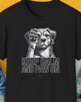 The black t-shirt features a cute dog design with the phrase KEEP CALM AND PAW ON. Perfect for any proud dog owner. Designed by Dog Gang.