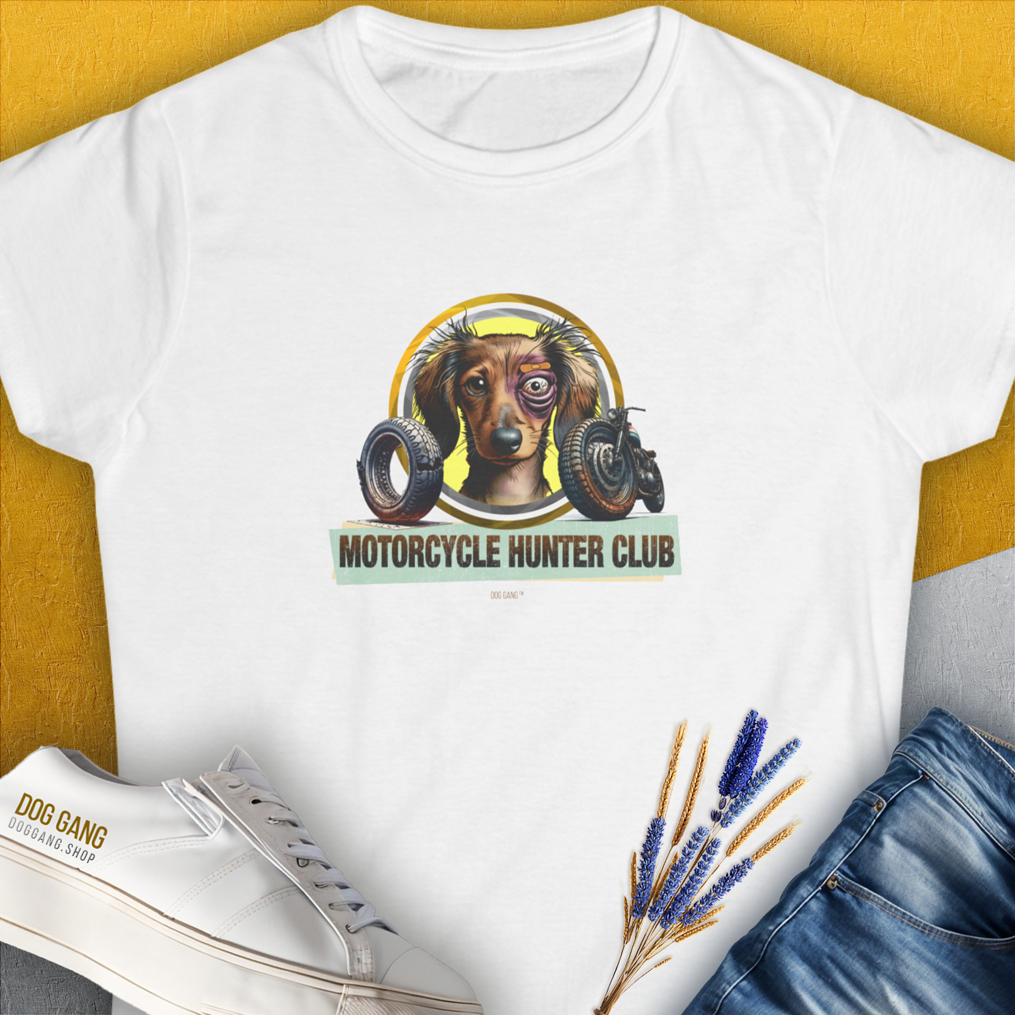 White Womens T-shirt featuring a a funny graphic of a slightly battered Dachshund with a black eye and the slogan "Motorcycle Hunter Club". Volume from the popular MOTORCYCLE HUNTER CLUB-series. Perfect for any ironic dog lover. Design by Dog Gang.