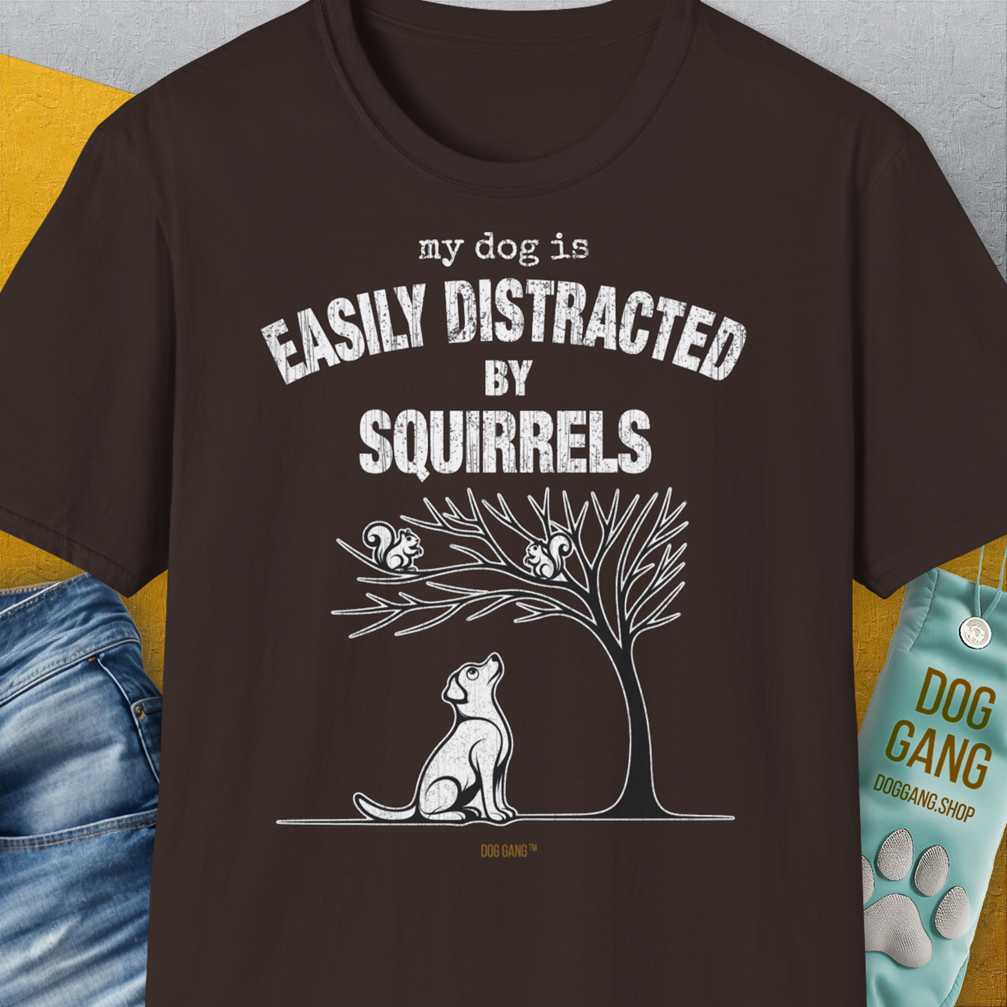 Funny dog shirt in dark chocolate: My Dog Is Easily Distracted By - Volume 1: Squirrels. Features a dog gazing at squirrels in a tree. Designed by Dog Gang.