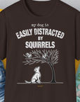 Funny dog shirt in dark chocolate: My Dog Is Easily Distracted By - Volume 1: Squirrels. Features a dog gazing at squirrels in a tree. Designed by Dog Gang.