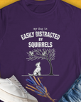 The purple shirt presents a funny dog watching squirrels, perfect for any dog lover. Designed by Dog Gang.