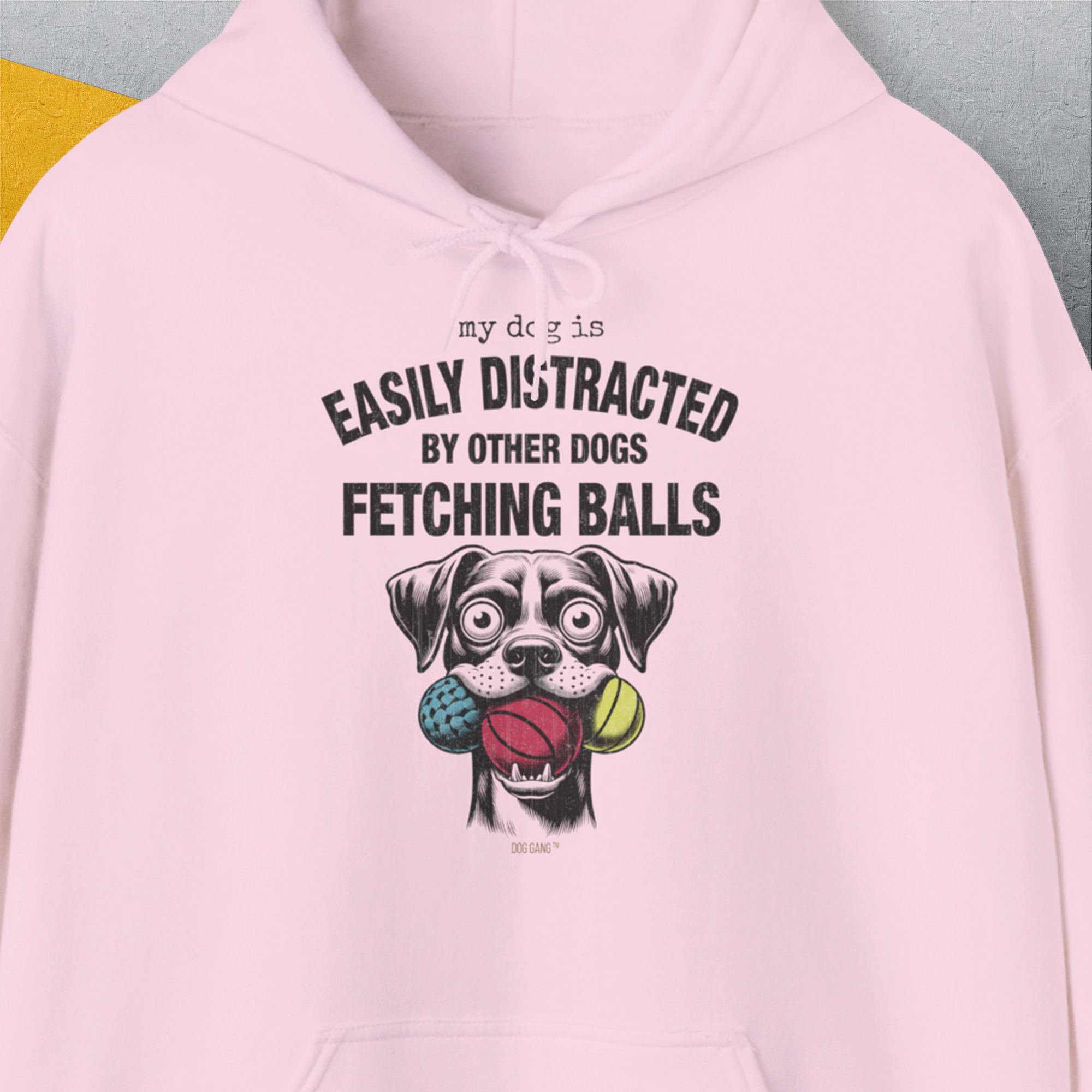 Unisex hoodie featuring a cartoon dog with balls and the quote My Dog Is Easily Distracted By - Volume 4: Other Dogs Fetching Balls in pink. A funny shirt for any dog lover. Designed by Dog Gang.