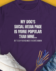 The "My Dogs Social Media Page Is More Popular Than Mine" womens T-shirt in purple features a funny dog quote, crafted from ringspun cotton. Designed by Dog Gang.