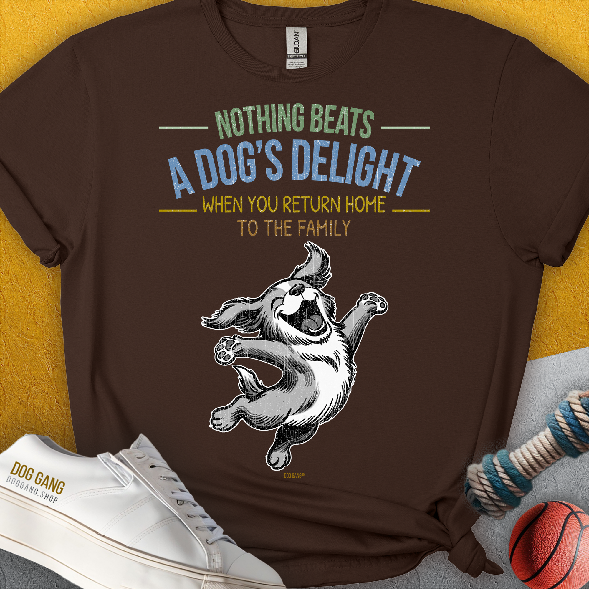 Braunes T-Shirt mit süsser und fröhlicher Hundegrafik und dem (englischsprachigen) Text: „Nichts übertrifft die Freude eines Hundes, wenn man nach Hause zur Familie zurückkehrt.“ Aus 100 % Baumwolle. Design von Dog Gang.