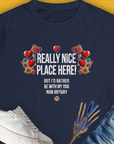 The Really Nice Place Here, Womens T-Shirt features a cute dog design intertwined with floral and heart elements. Text reads "Really nice place here! But I’d rather be with my dog now anyway." Designed by Dog Gang.