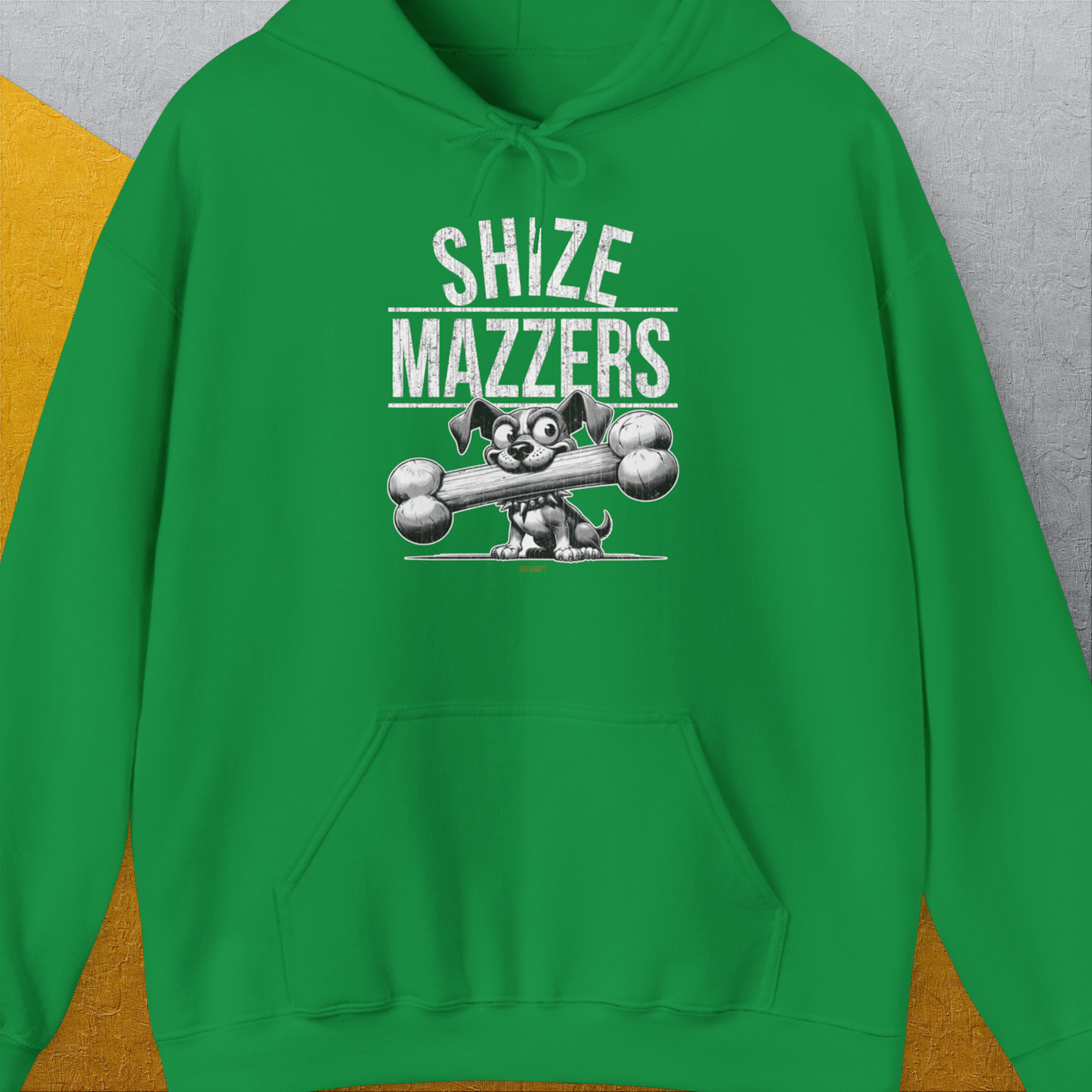 The Shize Mazzers, Volume 1 unisex hoodie showcases a funny dog design in Irish Green. A funny cartoon dog holding an oversized bone in its mouth, preventing it from speaking properly. The text reads "SHIZE MAZZERS". Perfect for any dog lover. Designed by Dog Gang.