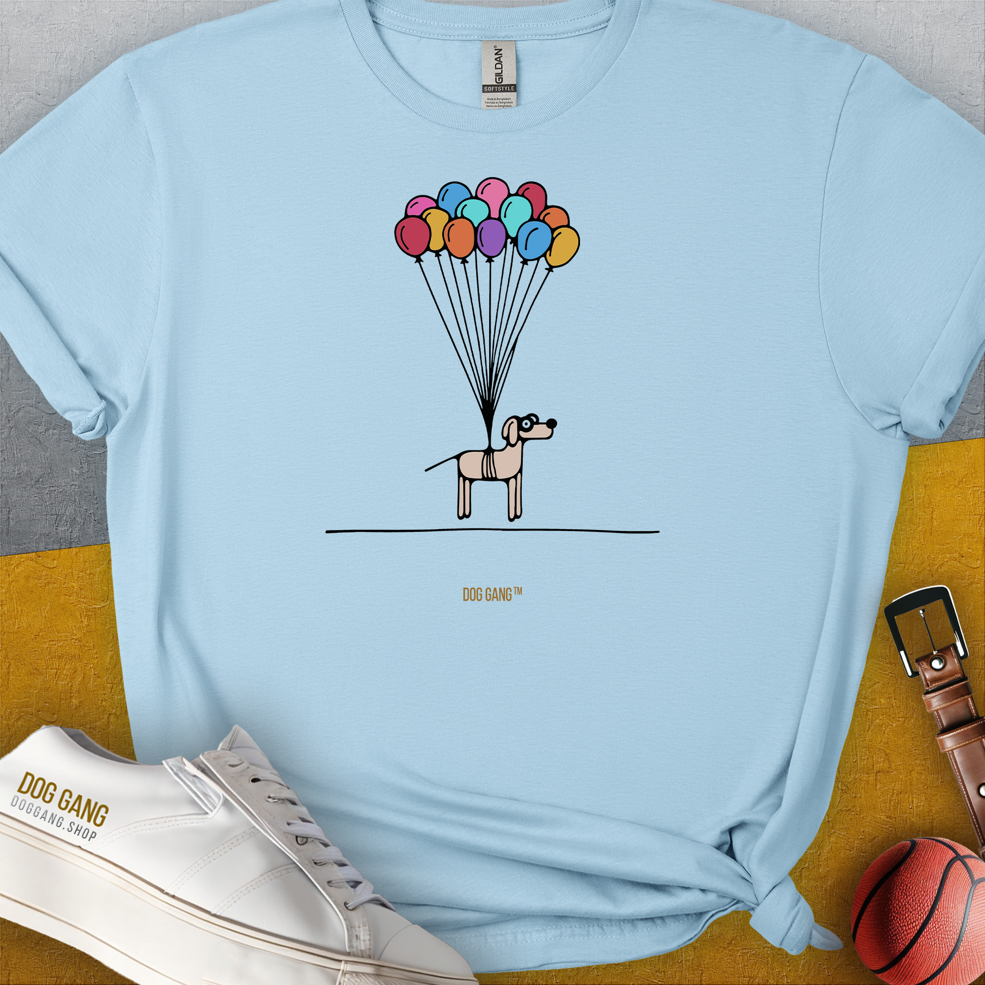 Funny dog shirt featuring a cartoon puppy floating slightly above the ground, held up by colorful balloons. Designed by Dog Gang.