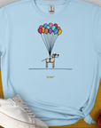 Funny dog shirt featuring a cartoon puppy floating slightly above the ground, held up by colorful balloons. Designed by Dog Gang.