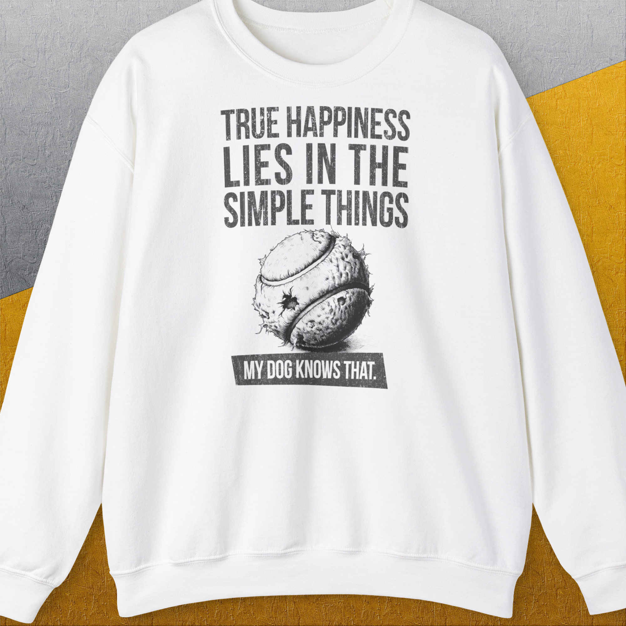 White unisex sweatshirt features the phrase True happiness lies in the simple things. My dog knows that with a cute dog chew toy design. Perfect for any dog lover gift. Designed by Dog Gang.