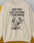 Das Unisex-Sweatshirt „Who Cares About The Weather When Youre In Good Company, Volume 1“ mit einer Illustration einer Person und eines Hundes beim Planschen durch Wassepfützen im Regen. Design von Dog Gang.