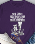 Purple Womens T-Shirt with a funny dog and boots splashing in water. Saying: Who Cares About The Weather When Youre In Good Company, Volume 2. Designed by Dog Gang.