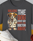 Dieses dunkel meliertfarbene Unisex-T-Shirt „Walking The Dog Every Day Keeps The Doctor Away, Volume 1“ passt perfekt in jede Garderobe. Es besteht aus 100 % weicher Baumwolle und zeigt einen Cartoon-Hund im Arztmantel und einen verspielten Text.