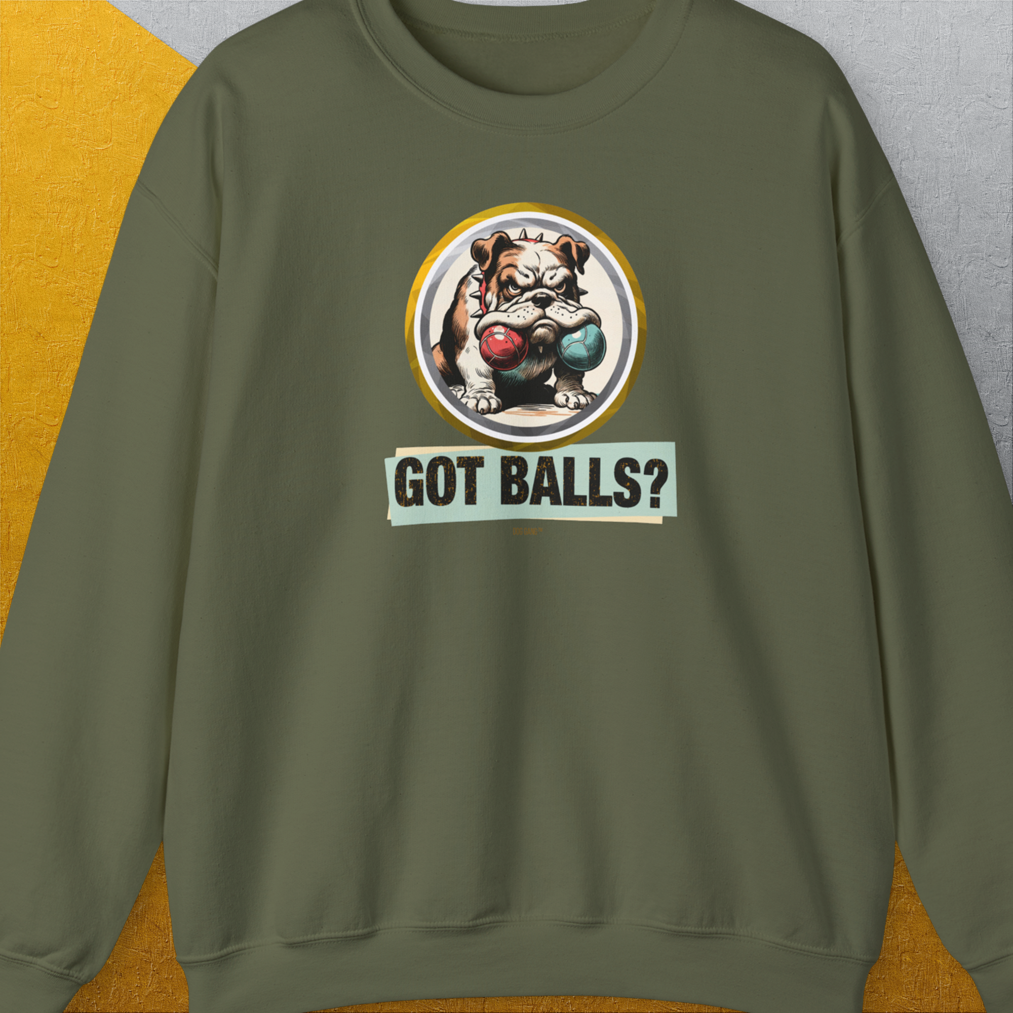 The Got Balls? Volume 1, Unisex Sweatshirt in Military Green showcases a funny bulldog graphic with 2 fetch balls in his mouth and playful text on the front. Designed by Dog Gang.