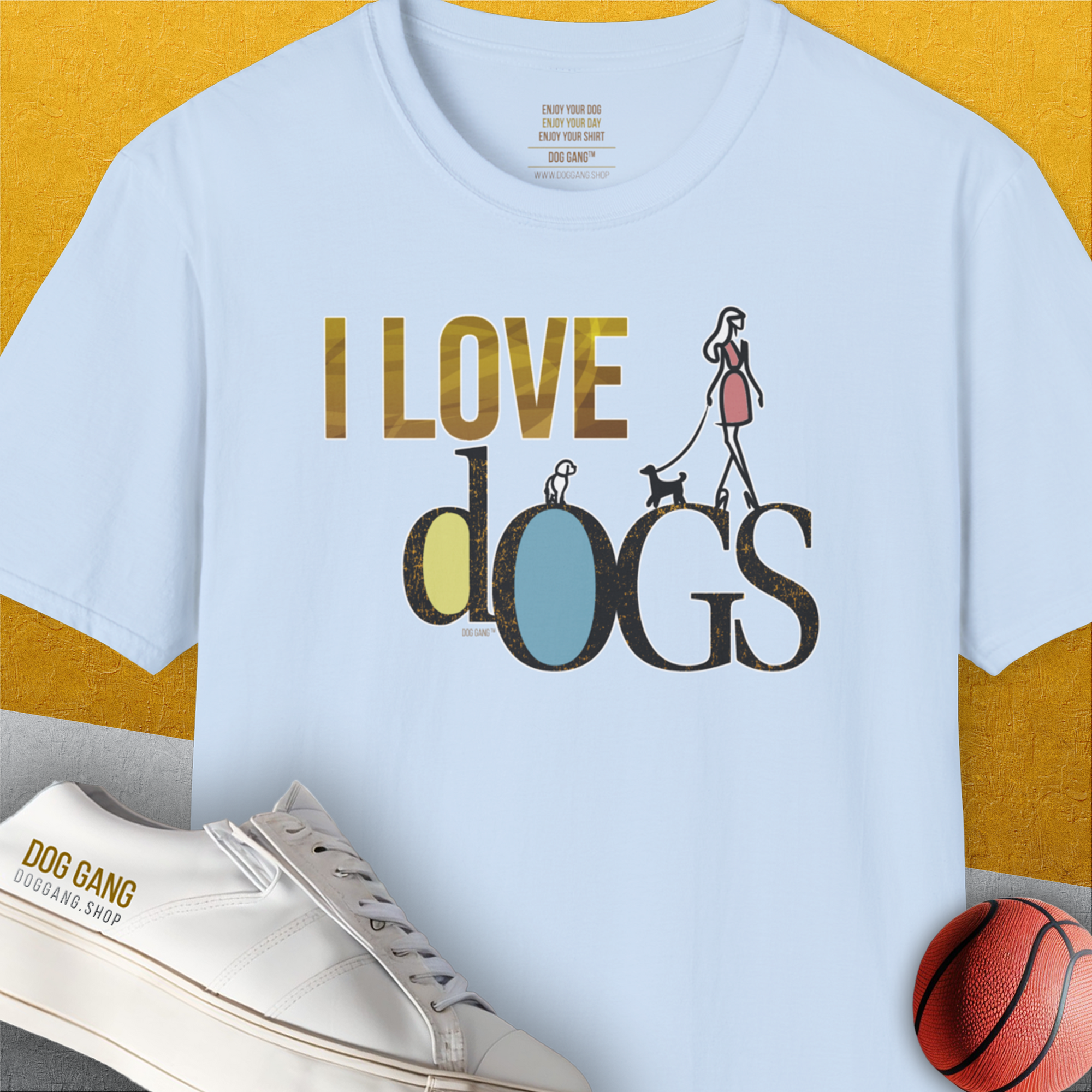 The unisex T-shirt features a woman walking dogs with the phrase I LOVE DOGS. A perfect dog lover gift, this light blue, 100% cotton tee is stylish and comfortable. Designed by Dog Gang.