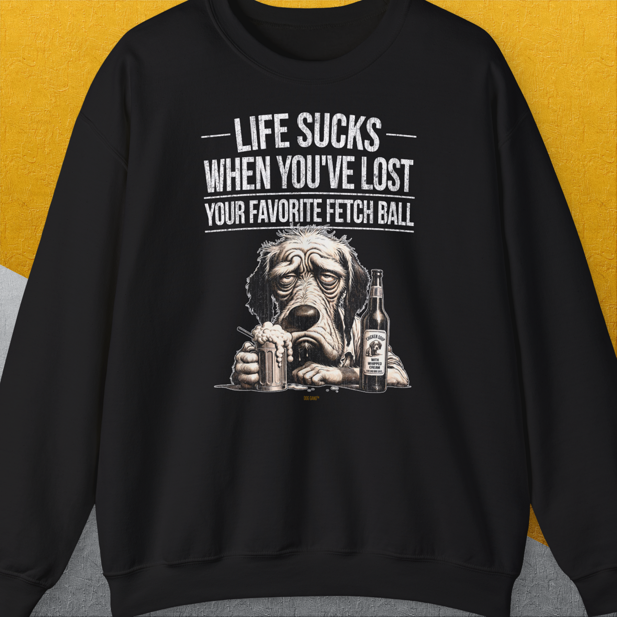 Sweatshirt mit einem lustig gezeichneten traurigen Hund mit eine Flasche (Flaschentikett: "Chicken Soup with whipped cream, for sad dog days") und dem Text „Life Sucks When You've Lost Your Favorite Fetch Ball“. Design vom Schweize Label Dog Gang.