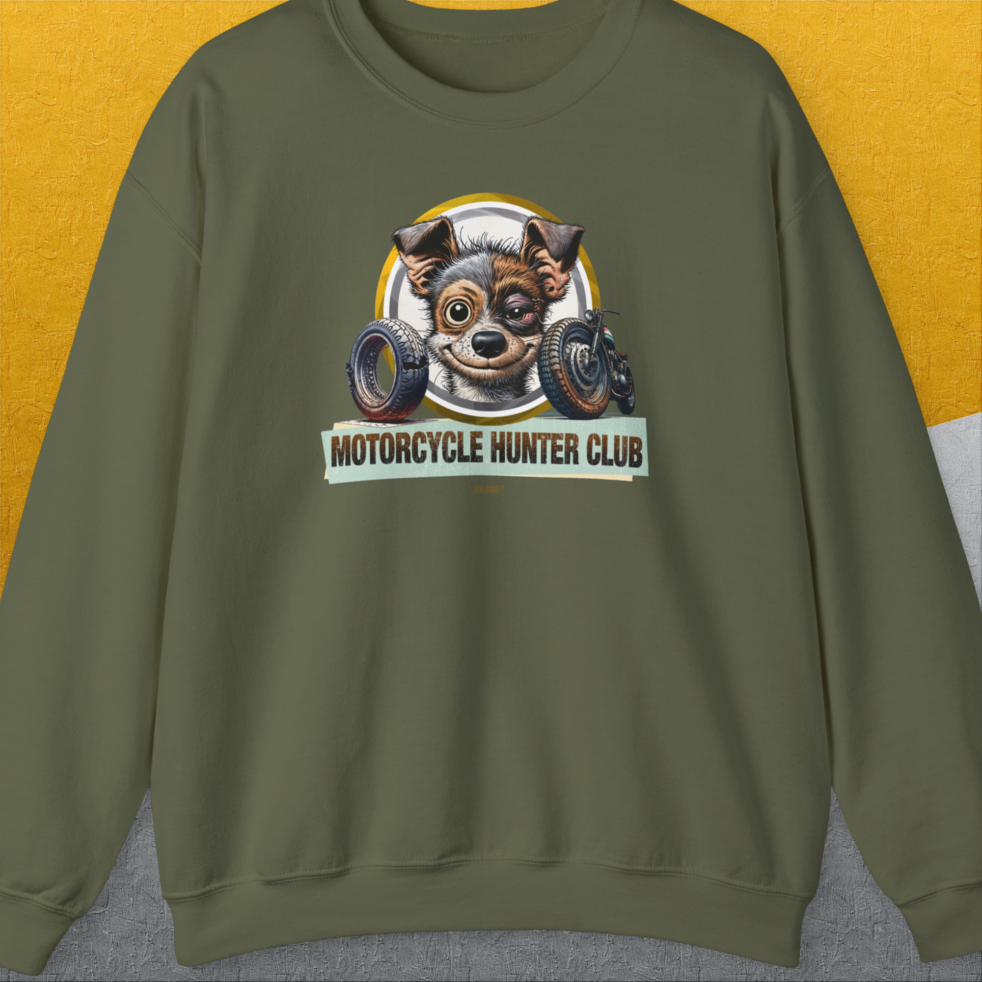 The Motorcycle Hunter Club, Volume 1 Unisex Sweatshirt in military green features a cute slightly battered dog with a black eye and the humorous slogan "Motorcycle Hunter Club". Designed by Dog Gang. A great gift for any dog ​​lover, or as a fun gift.
