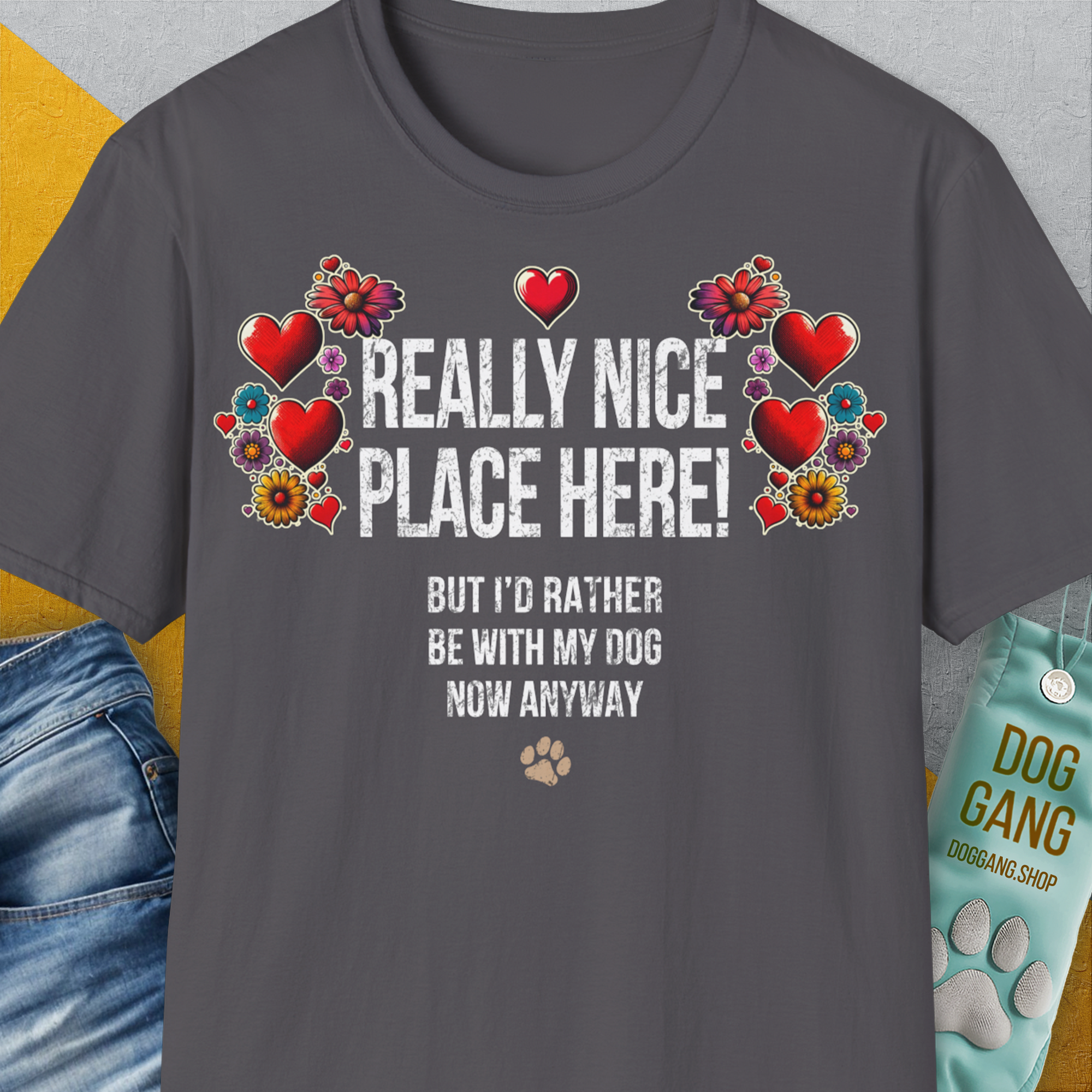 Anthrazitfarbenes Unisex-T-Shirt aus weicher Baumwolle mit Herz- und Blumenmuster. Darauf steht auf englisch: „Wirklich schöner Ort hier! Aber ich wäre jetzt sowieso lieber bei meinem Hund.“ Design von Dog Gang.