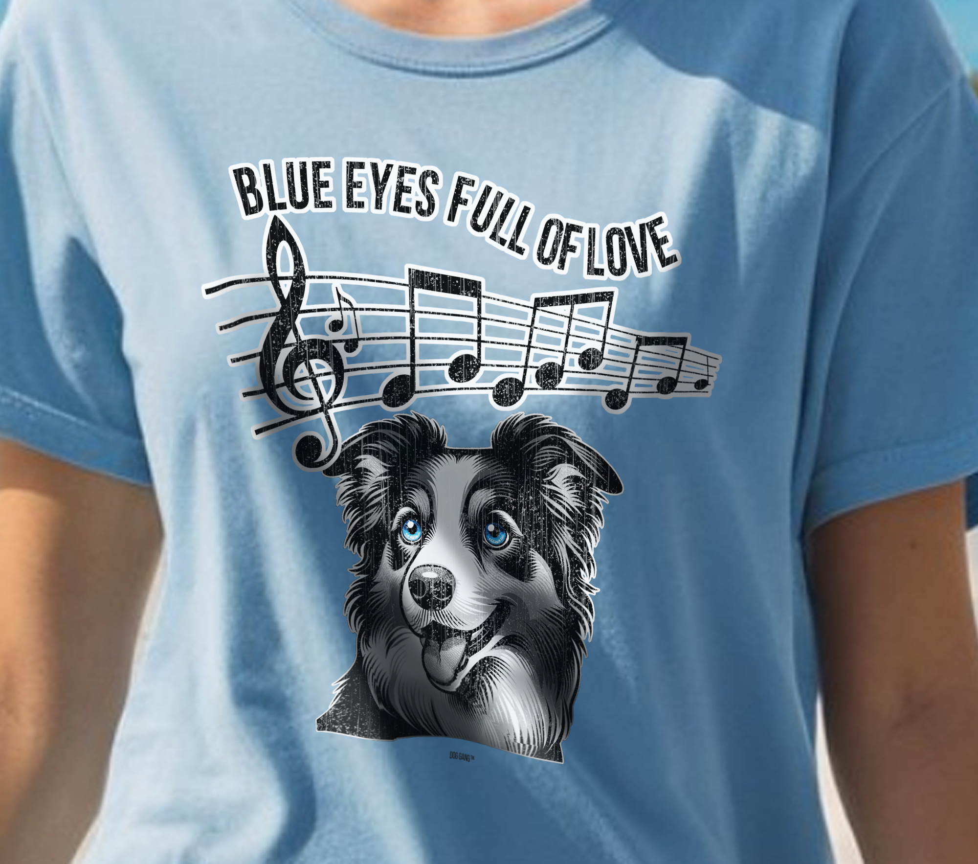 A person wearing a blue T-shirt featuring a graphic of a dog with blue eyes below musical notes and the text Blue Eyes Full of Love.