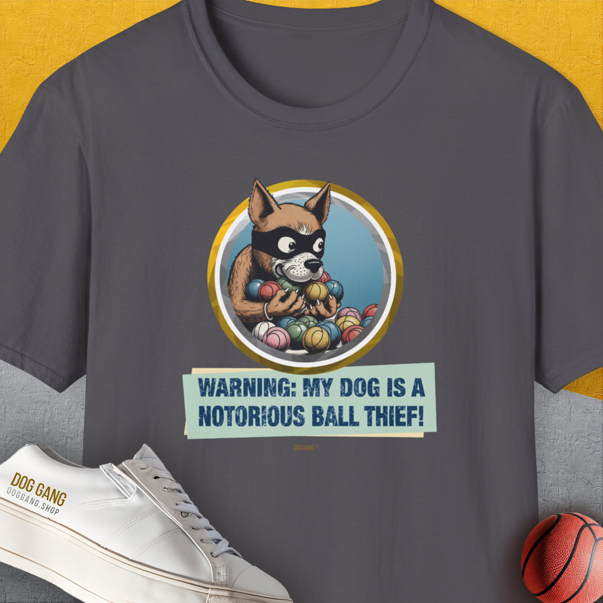 Charcoal soft-style 100% cotton unisex T-shirt featuring a masked dog illustration and Warning: My Dog Is A Notorious Ball Thief! text. Perfect for any dog owner with a sense of humor. Designed by Dog Gang.