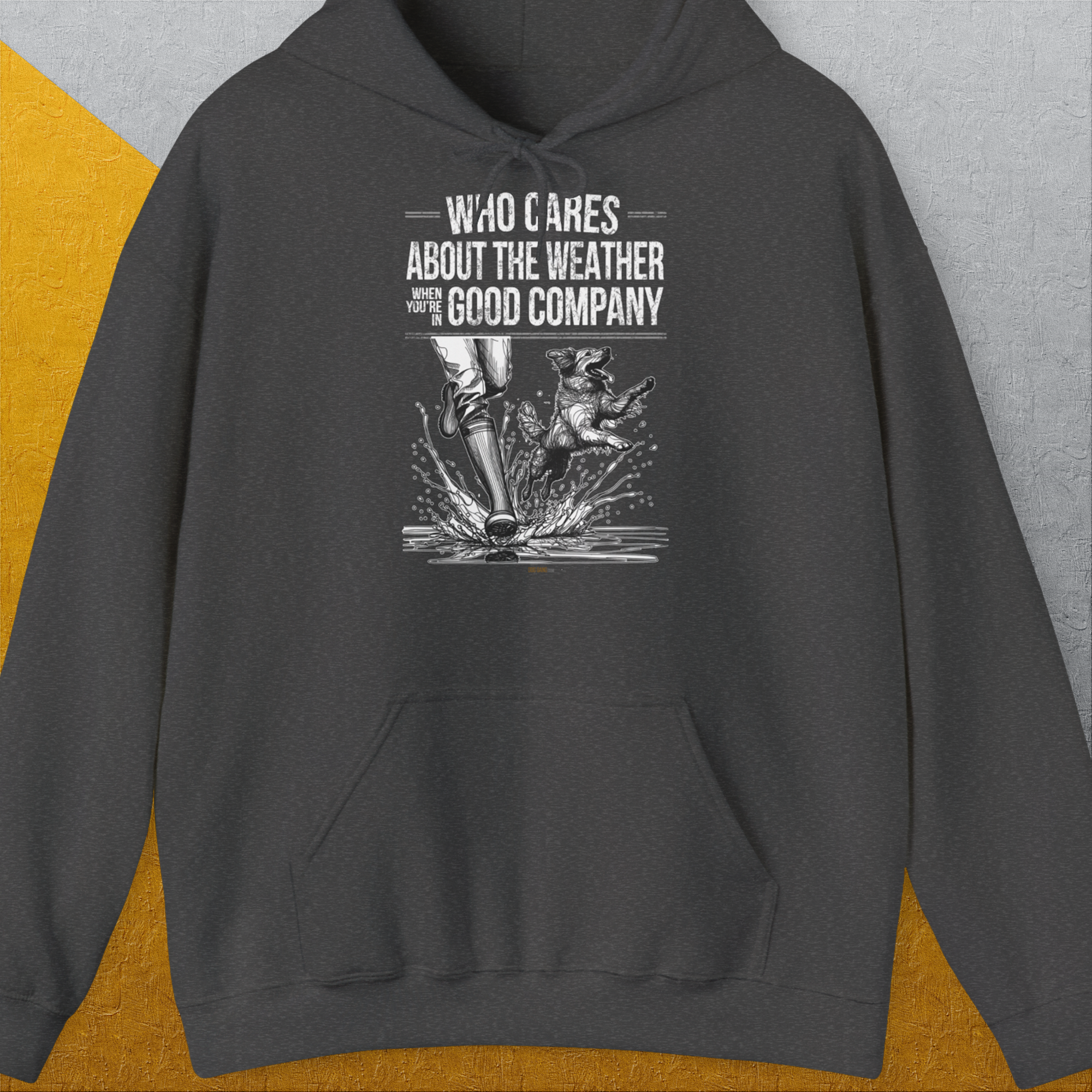 Der Unisex-Kapuzenpullover Volume 1 in Dark Heather trägt den Aufdruck „Who Cares About The Weather When You're In Good Company?“ und ein Design mit den Gummistiefeln einer Person und einem Hund, die durchs Wasser laufen. Entworfen von Dog Gang.