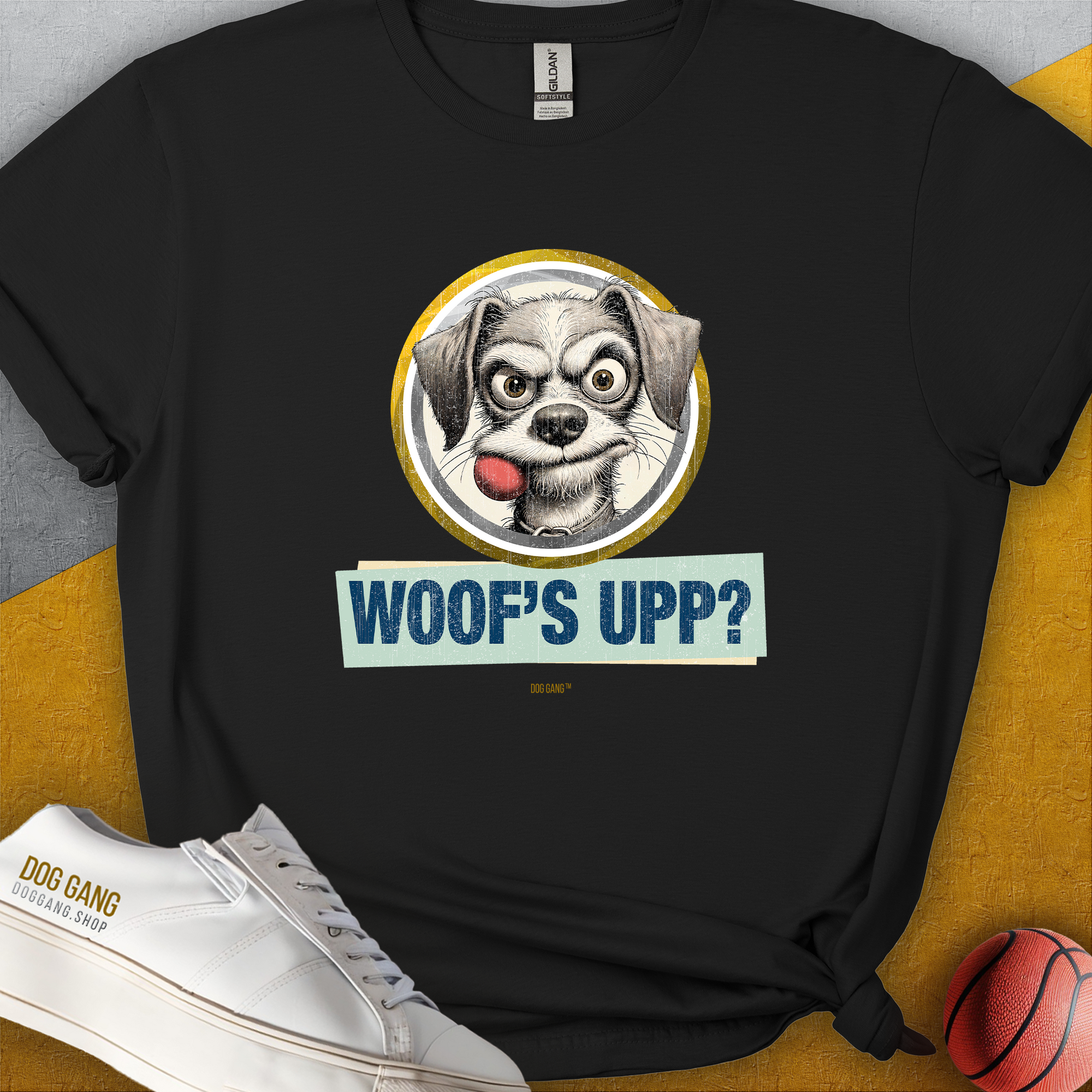 The Woofs Upp? Volume 1 T-shirt features a cartoon dog with a fetch ball in his mouth and the phrase "WOOFS UPP?" Perfect for any dog lover, its a fun and playful design. Designed by Dog Gang.
