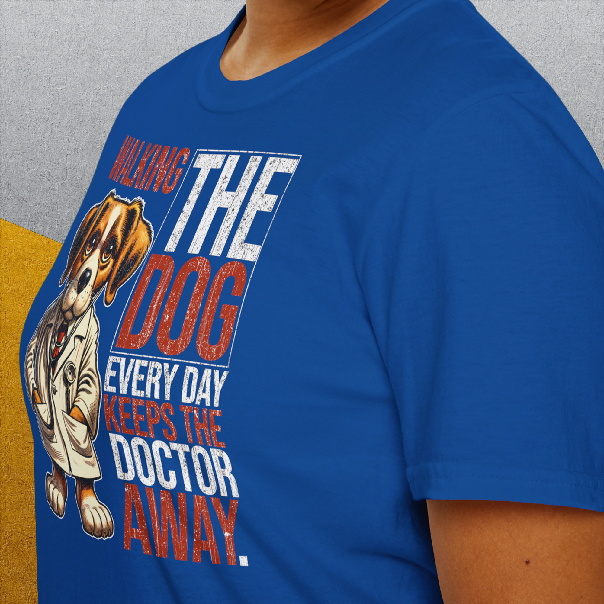 Jemand trägt ein blaues Unisex-T-Shirt mit dem Titel „Walking The Dog Every Day Keeps The Doctor Away, Volume 1“. Es besteht aus 100 % Baumwolle, zeigt einen Cartoon-Hund und verspricht Komfort und Stil für jedermann.